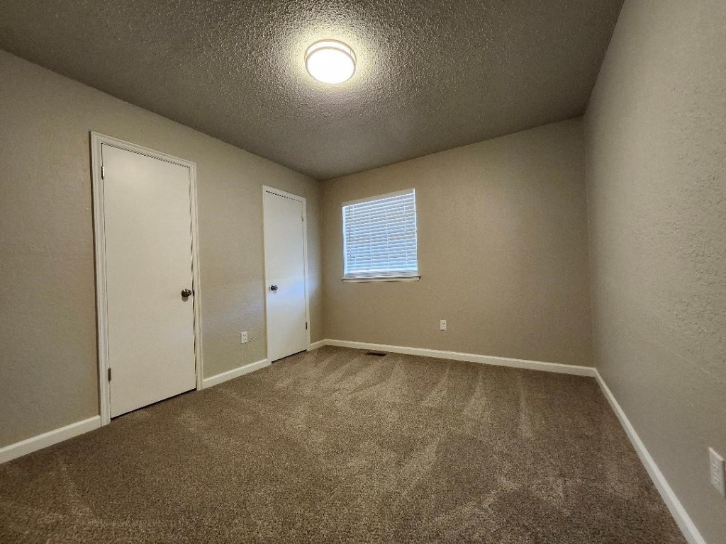 9800 S Country Club Drive, Oklahoma City, OK 73159 unfurnished bedroom with carpet and a textured ceiling
