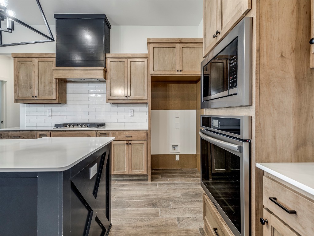 143 Primrose Point Avenue, Piedmont, OK 73078 kitchen with premium range hood, backsplash, stainless steel appliances, light hardwood / wood-style floors, and a center island