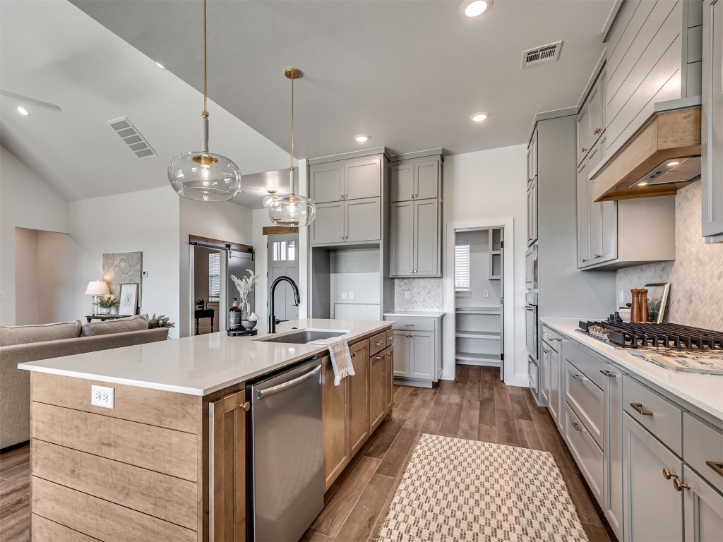 446 Venetian Avenue, Piedmont, OK 73078 kitchen with premium range hood, stainless steel appliances, a center island with sink, sink, and dark hardwood / wood-style flooring