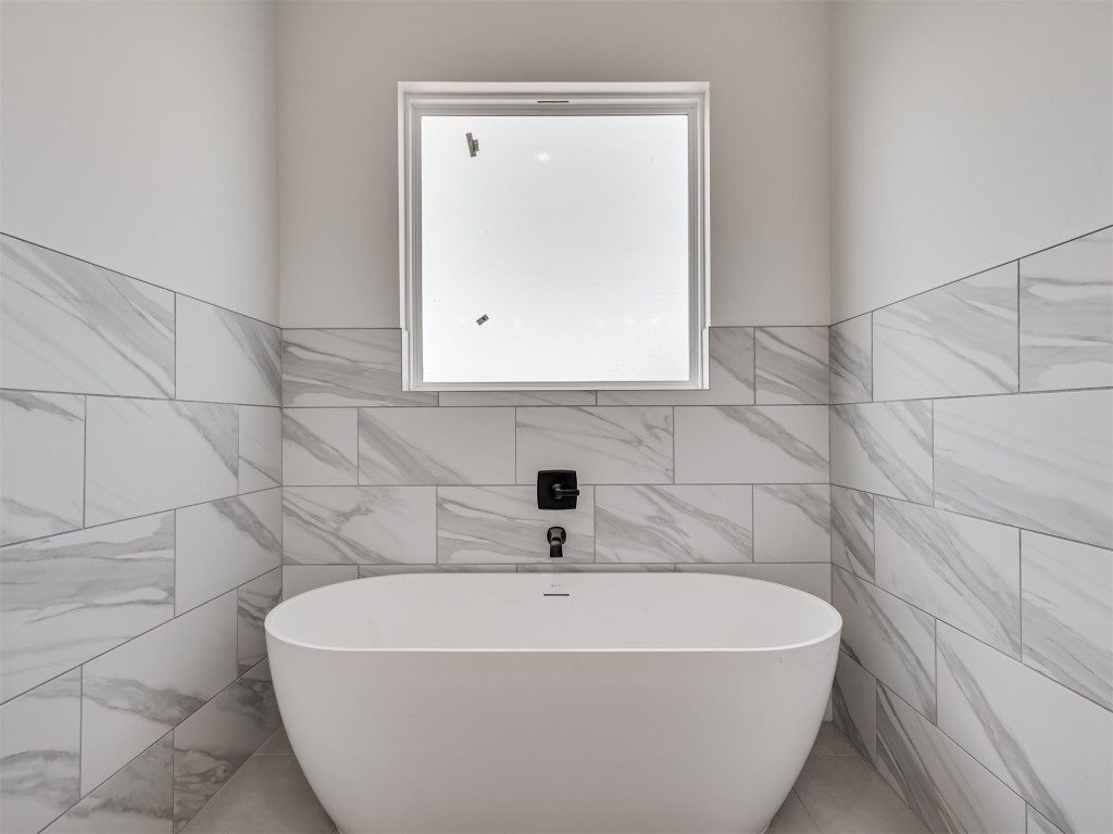 508 Venetian Avenue, Piedmont, OK 73078 bathroom featuring tile walls, tile floors, and a washtub