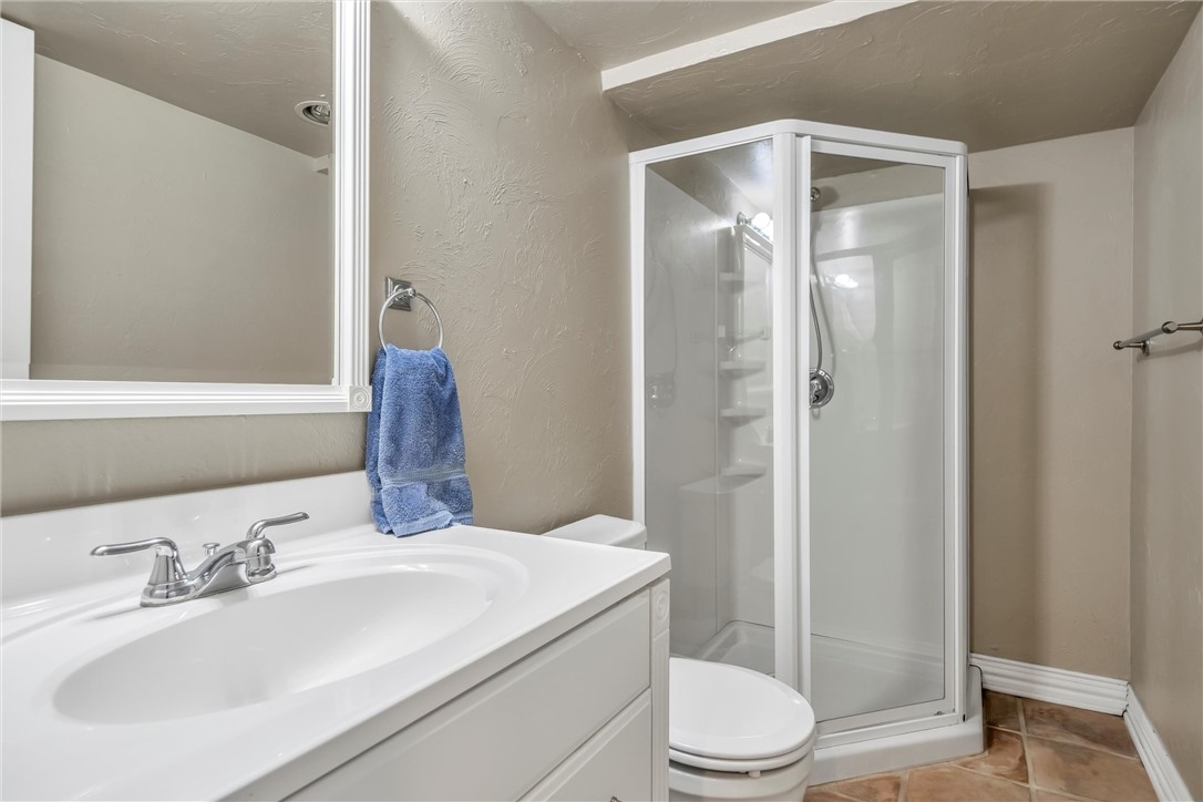 1117 Tedford Way, Nichols Hills, OK 73116 bathroom featuring a shower with door, toilet, oversized vanity, and tile flooring