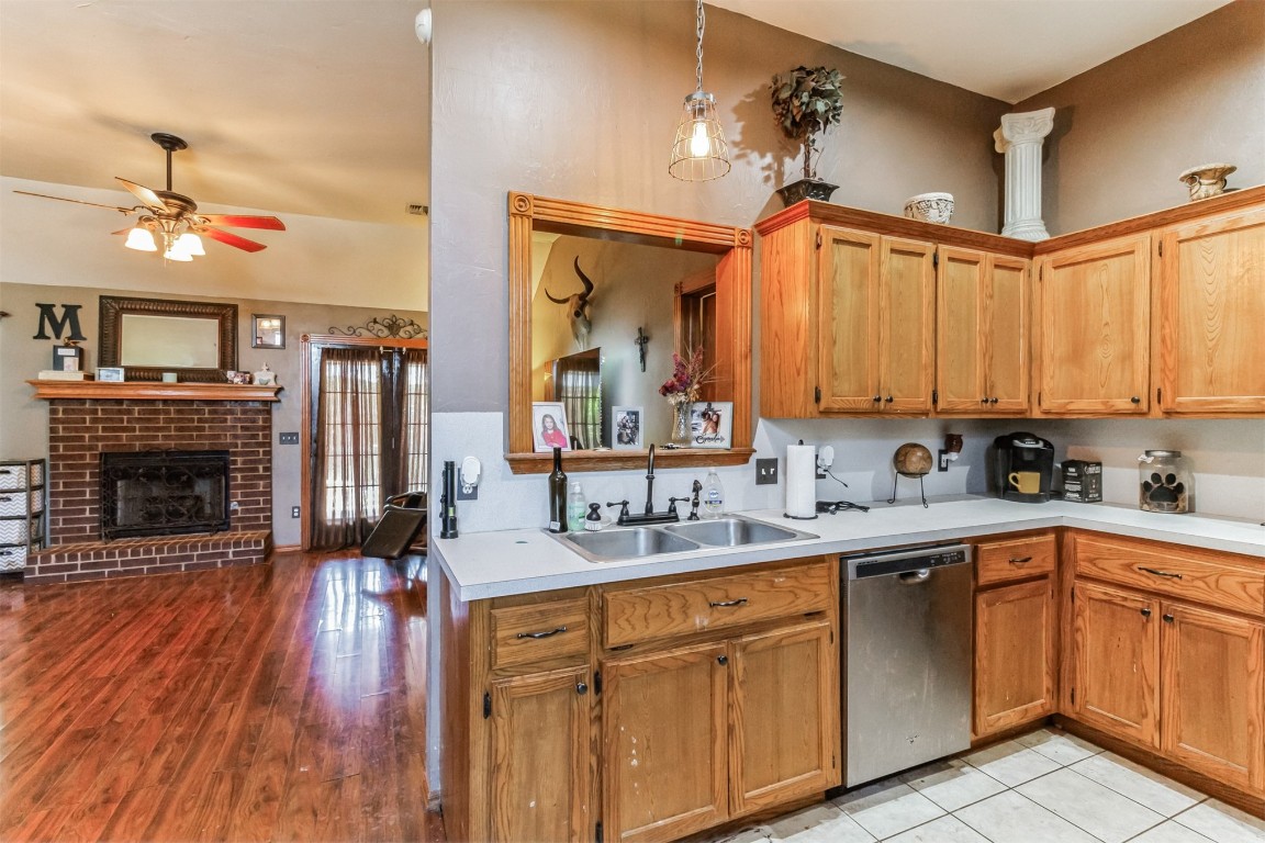 428 E Magnolia Terrace, Mustang, OK 73064 kitchen featuring a brick fireplace, ceiling fan, dishwasher, sink, and light tile floors