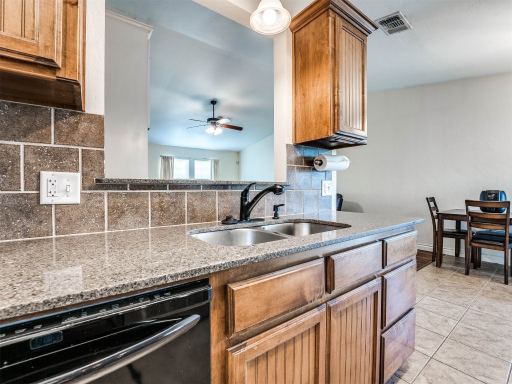 1113 SW 155th Street, Oklahoma City, OK 73170 kitchen featuring ceiling fan, sink, backsplash, black dishwasher, and light stone countertops