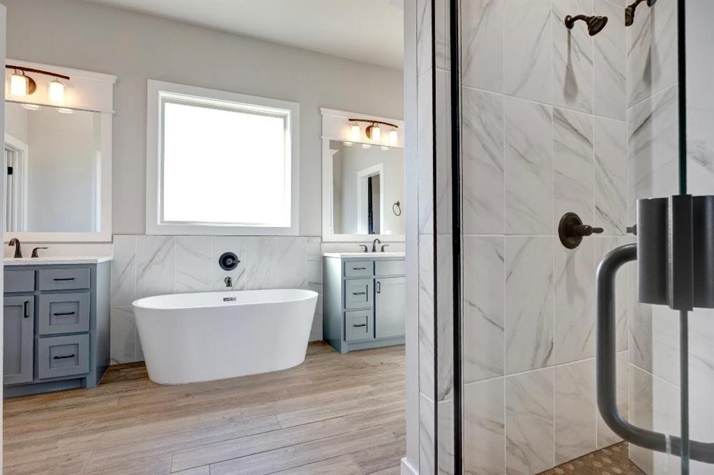 6301 NW 153rd Street, Edmond, OK 73013 bathroom featuring hardwood / wood-style flooring, tiled shower, tile walls, and large vanity