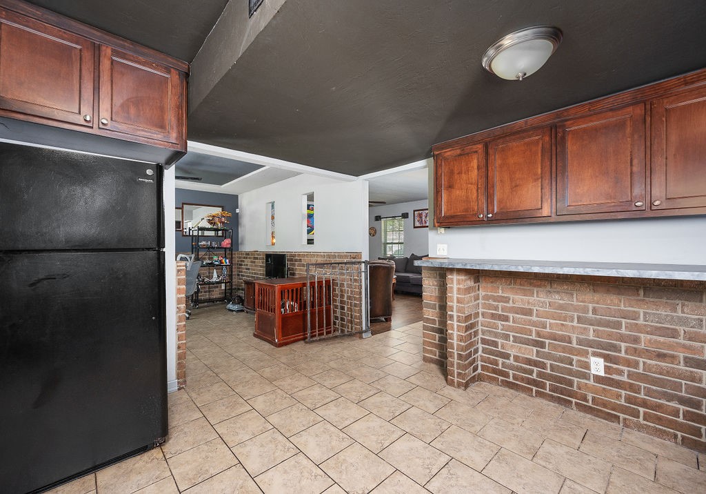 205 Vickie Drive, Del City, OK 73115 kitchen featuring brick wall, black fridge, and light tile floors