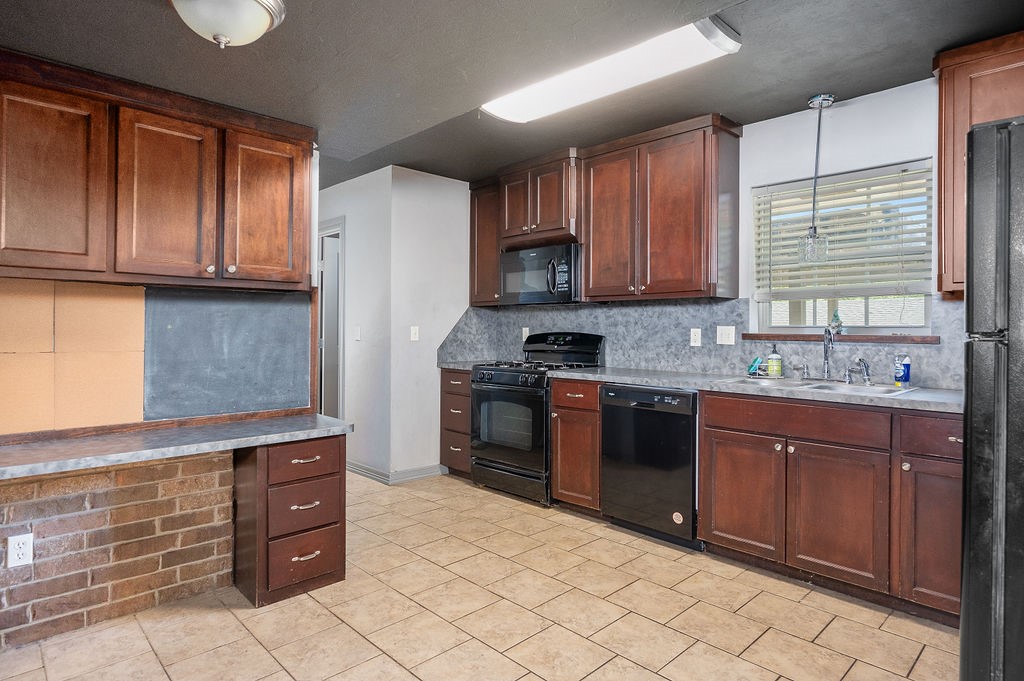 205 Vickie Drive, Del City, OK 73115 kitchen with light tile floors, sink, backsplash, decorative light fixtures, and black appliances