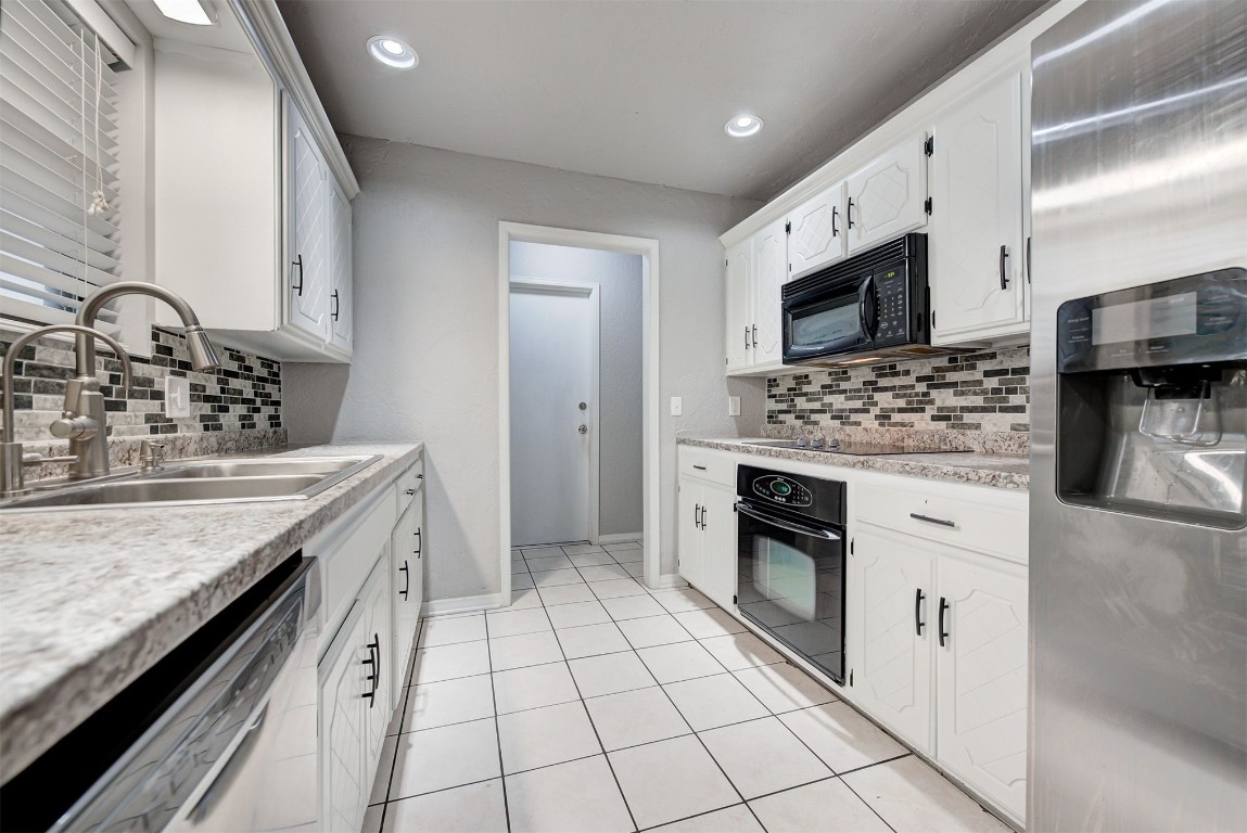 7728 Northgate Avenue, Oklahoma City, OK 73162 kitchen with backsplash, white cabinetry, light tile floors, and black appliances