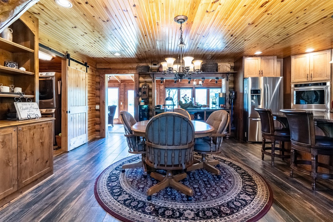 Address Hidden dining space with wooden walls, a barn door, dark wood-type flooring, and wooden ceiling