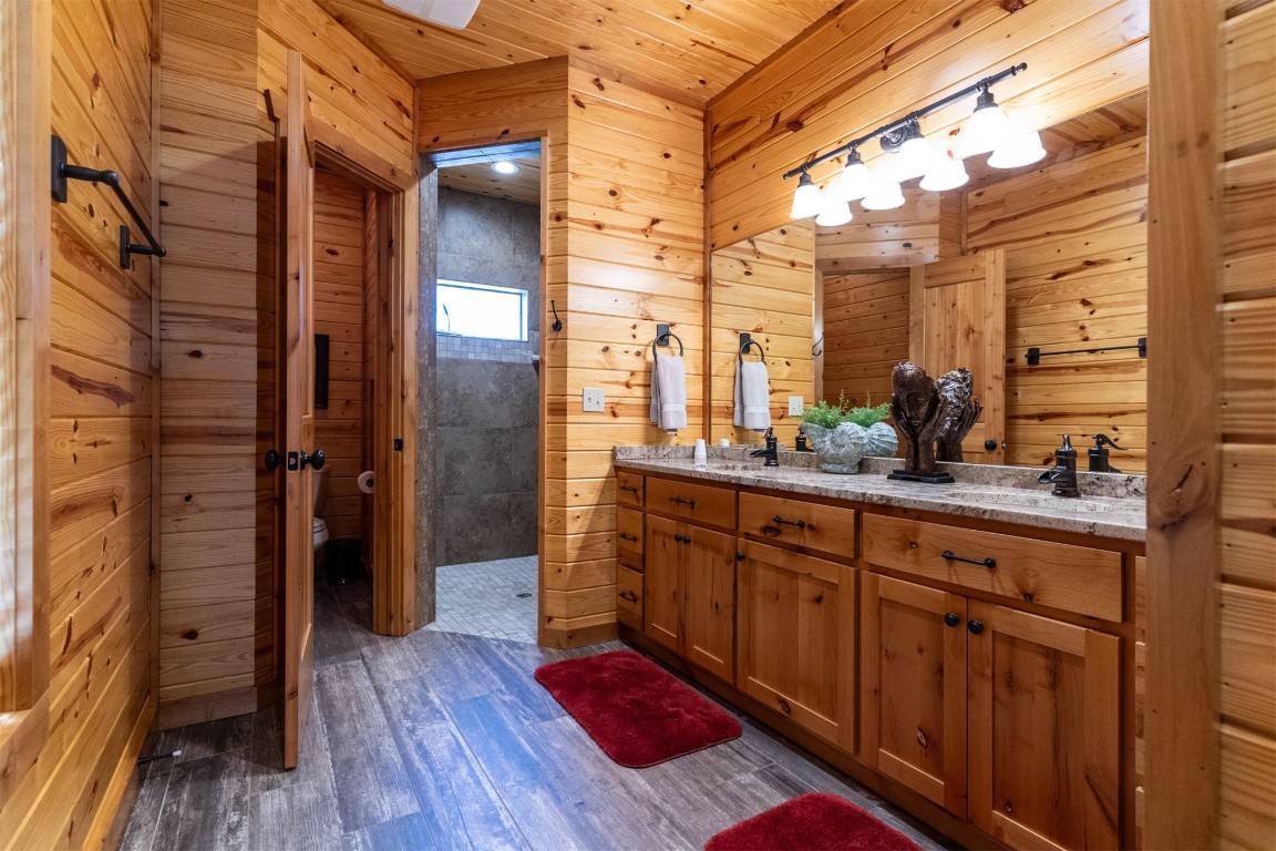 Address Hidden bathroom featuring double vanity, hardwood / wood-style flooring, and wooden walls