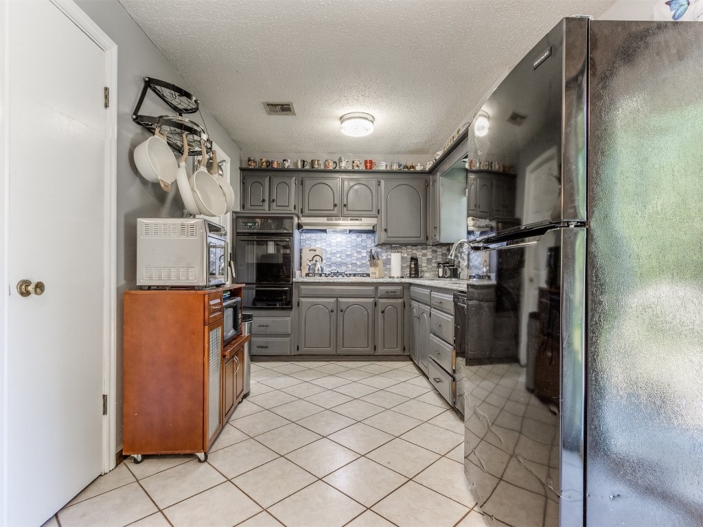5216 S Briarwood Drive, Oklahoma City, OK 73135-1412 kitchen featuring gray cabinetry, light tile flooring, black appliances, tasteful backsplash, and sink