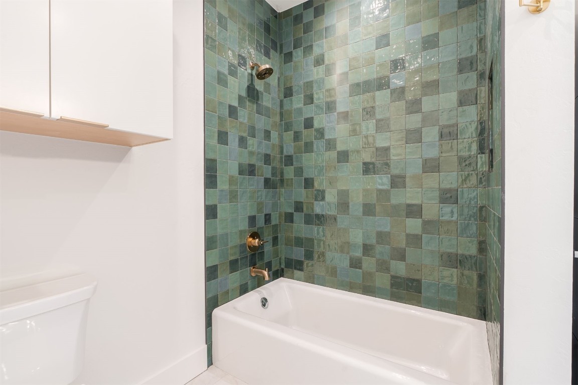 15613 Woodleaf Lane, Edmond, OK 73013 bathroom featuring toilet, tiled shower / bath, and tile flooring