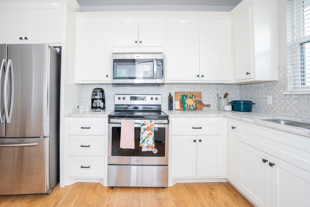 2508 Thornberry Lane, Yukon, OK 73099 kitchen featuring appliances with stainless steel finishes, light hardwood / wood-style flooring, backsplash, light stone counters, and white cabinets