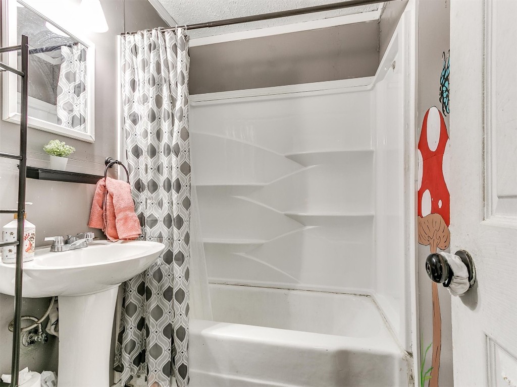 3833 SW 38TH Street, Oklahoma City, OK 73119 bathroom with shower / bath combination with curtain and a textured ceiling
