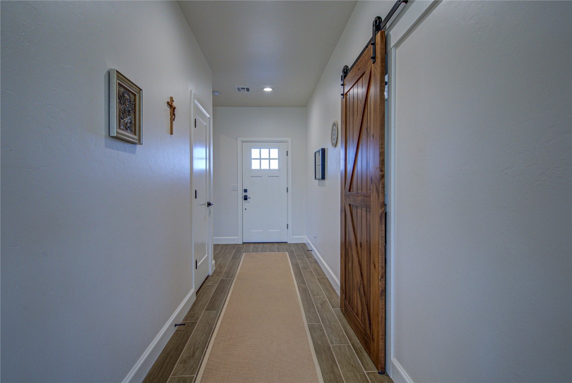 12656 Bridlewood Lane, Blanchard, OK 73010 corridor featuring a barn door and hardwood / wood-style floors