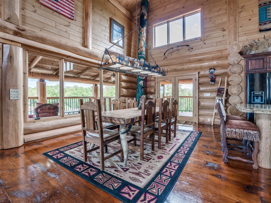 2050 S Henney Road, Guthrie, OK 73044 dining area featuring dark hardwood / wood-style floors, a towering ceiling, and log walls