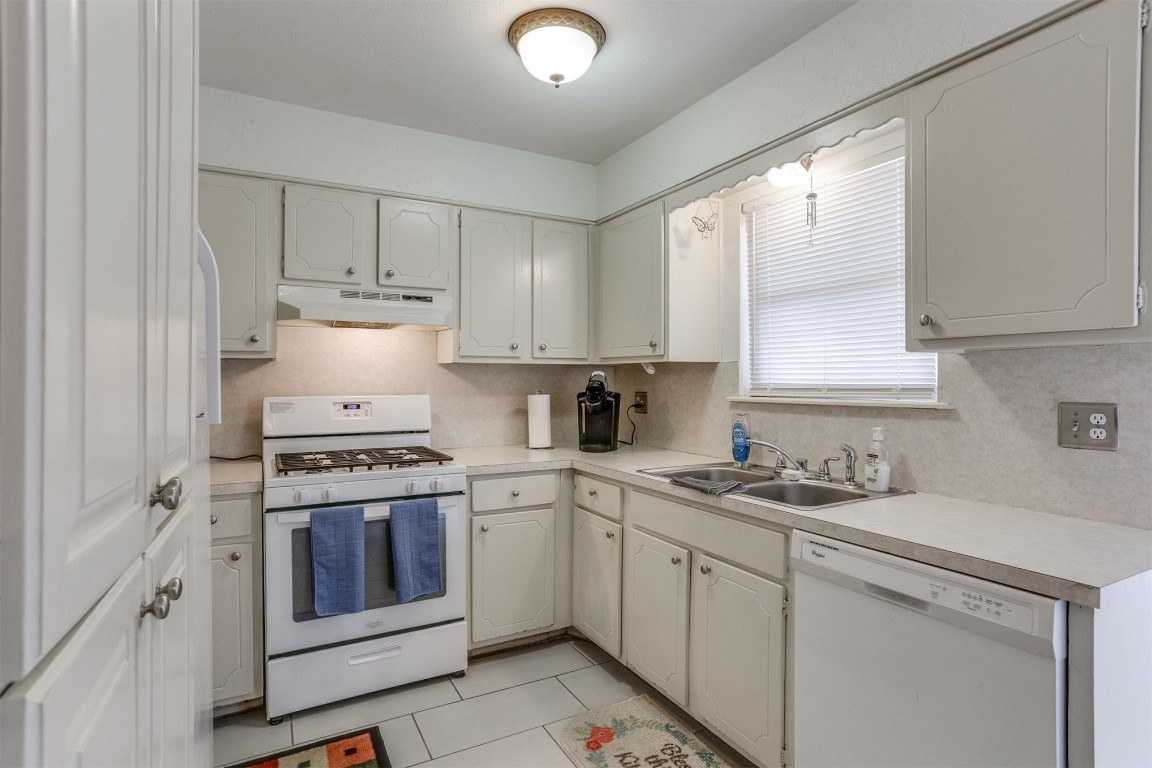 6732 N Meridian Avenue, #E, Oklahoma City, OK 73116 kitchen featuring light tile floors, white cabinets, sink, white appliances, and tasteful backsplash