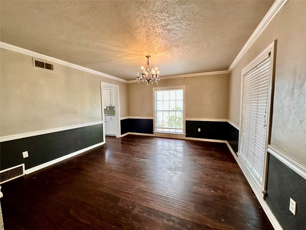 4311 N Georgia Avenue, Oklahoma City, OK 73118 spare room featuring dark hardwood / wood-style floors, crown molding, a chandelier, and a textured ceiling