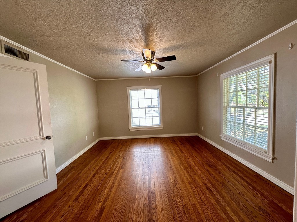 4311 N Georgia Avenue, Oklahoma City, OK 73118 spare room with crown molding, ceiling fan, dark hardwood / wood-style floors, and a textured ceiling