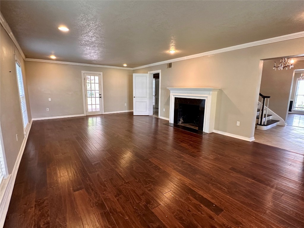 4311 N Georgia Avenue, Oklahoma City, OK 73118 unfurnished living room with ornamental molding, dark hardwood / wood-style floors, and a textured ceiling