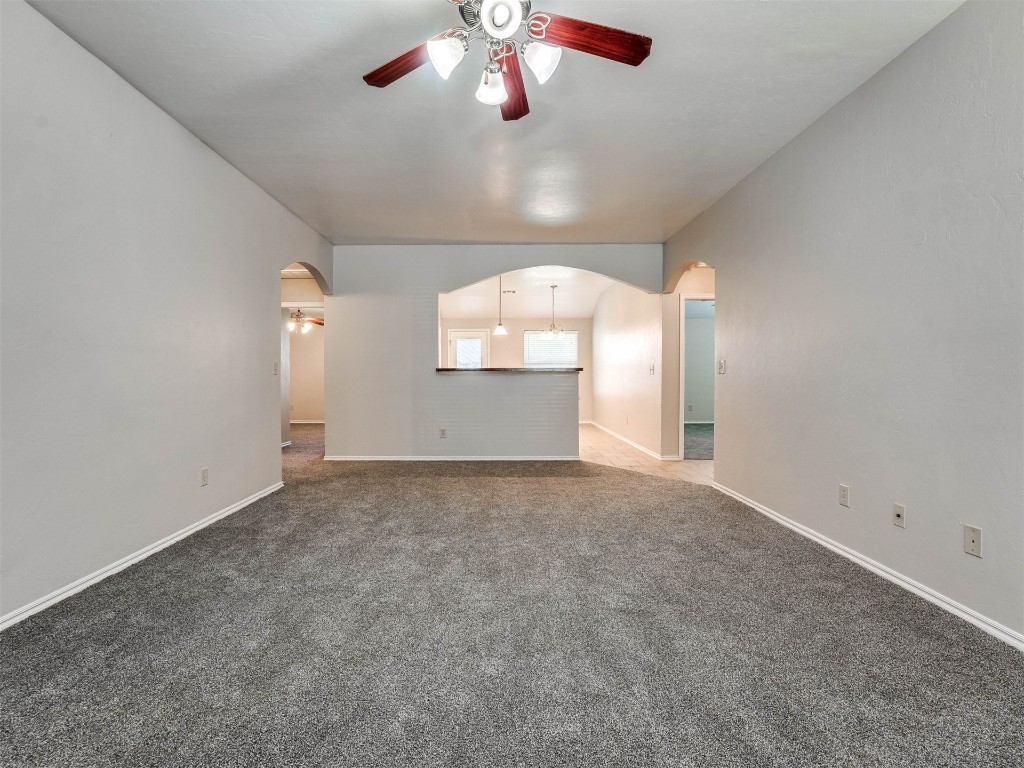 8613 SW 46th Place, Oklahoma City, OK 73179 unfurnished living room featuring ceiling fan and dark carpet