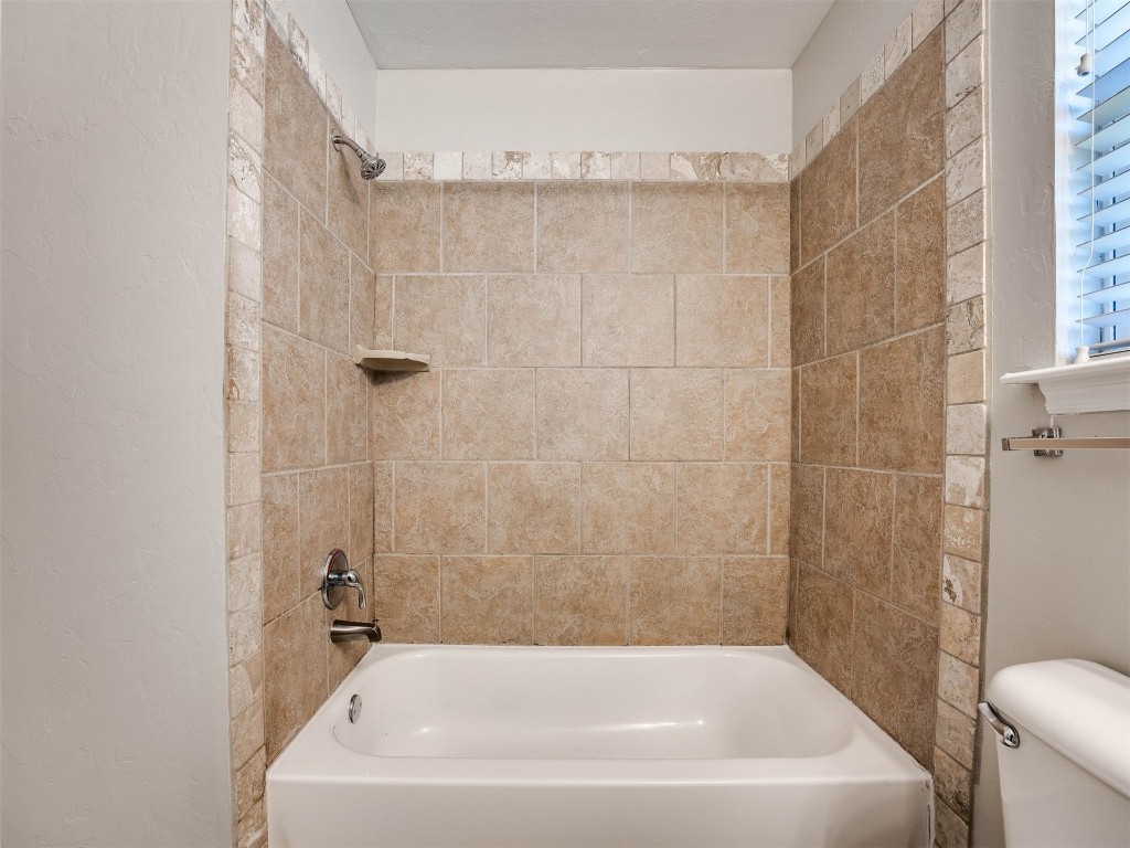 8613 SW 46th Place, Oklahoma City, OK 73179 bathroom with tiled shower / bath and toilet