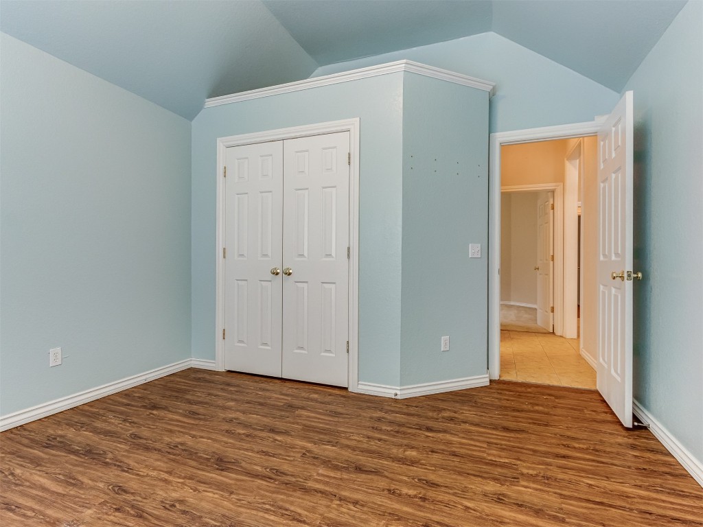 16605 Farmington Way, Edmond, OK 73012 unfurnished bedroom featuring hardwood / wood-style floors, vaulted ceiling, and a closet