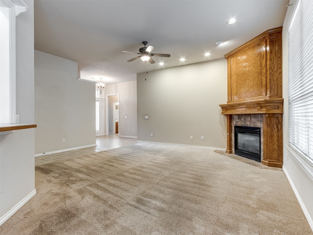 16605 Farmington Way, Edmond, OK 73012 unfurnished living room featuring light colored carpet, ceiling fan, and a tiled fireplace