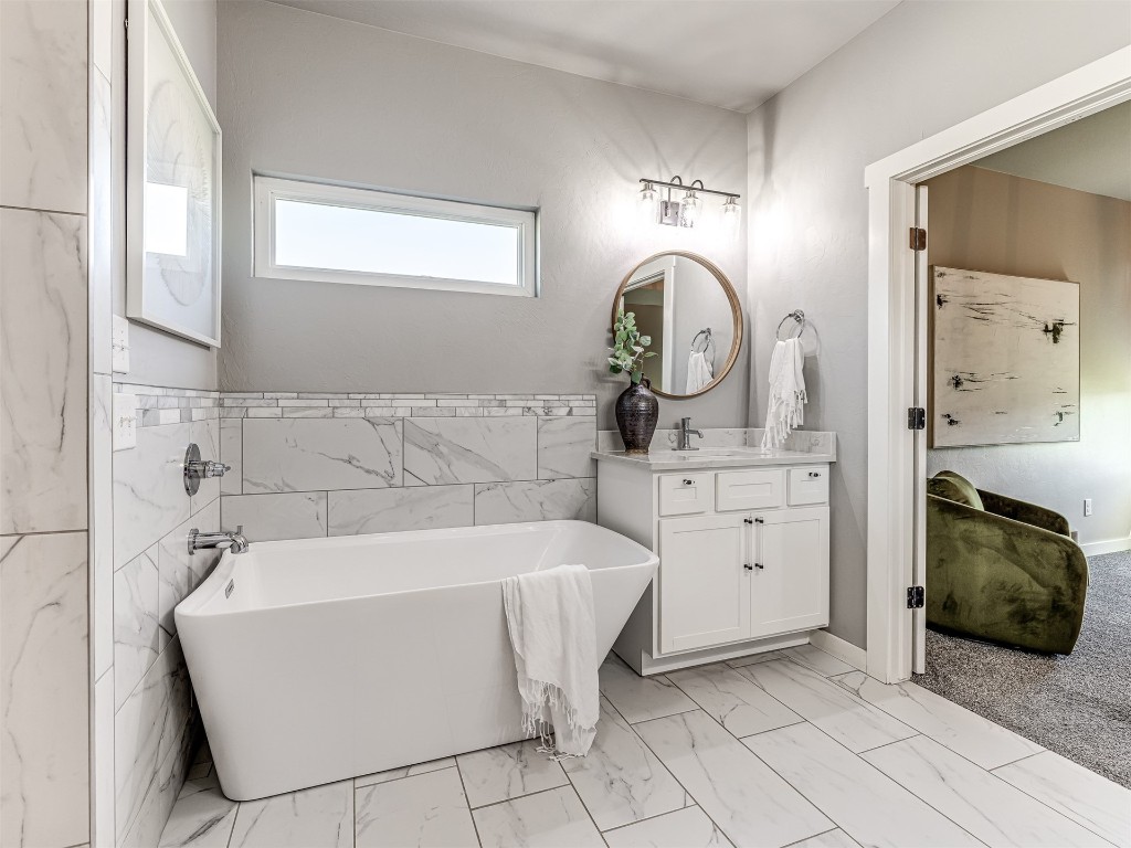 280 Old Farm Road, Edmond, OK 73034 bathroom with vanity with extensive cabinet space, tile floors, tile walls, and a tub
