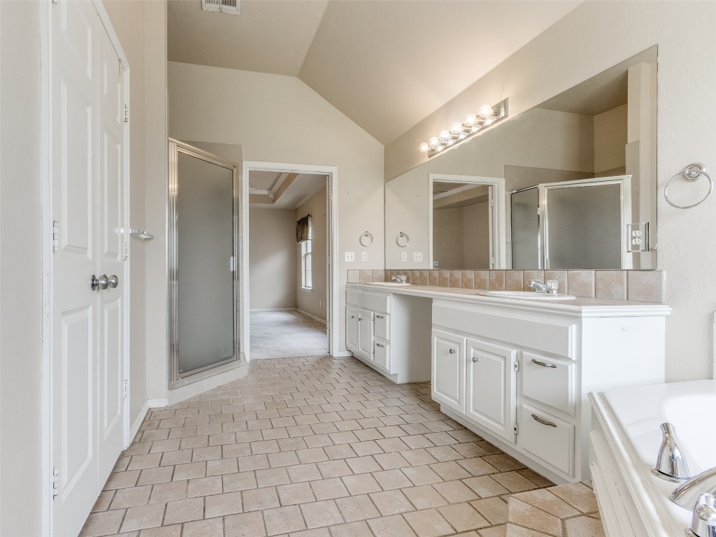 12109 Dalton Drive, Oklahoma City, OK 73162 bathroom with lofted ceiling, tasteful backsplash, vanity, shower with separate bathtub, and tile floors