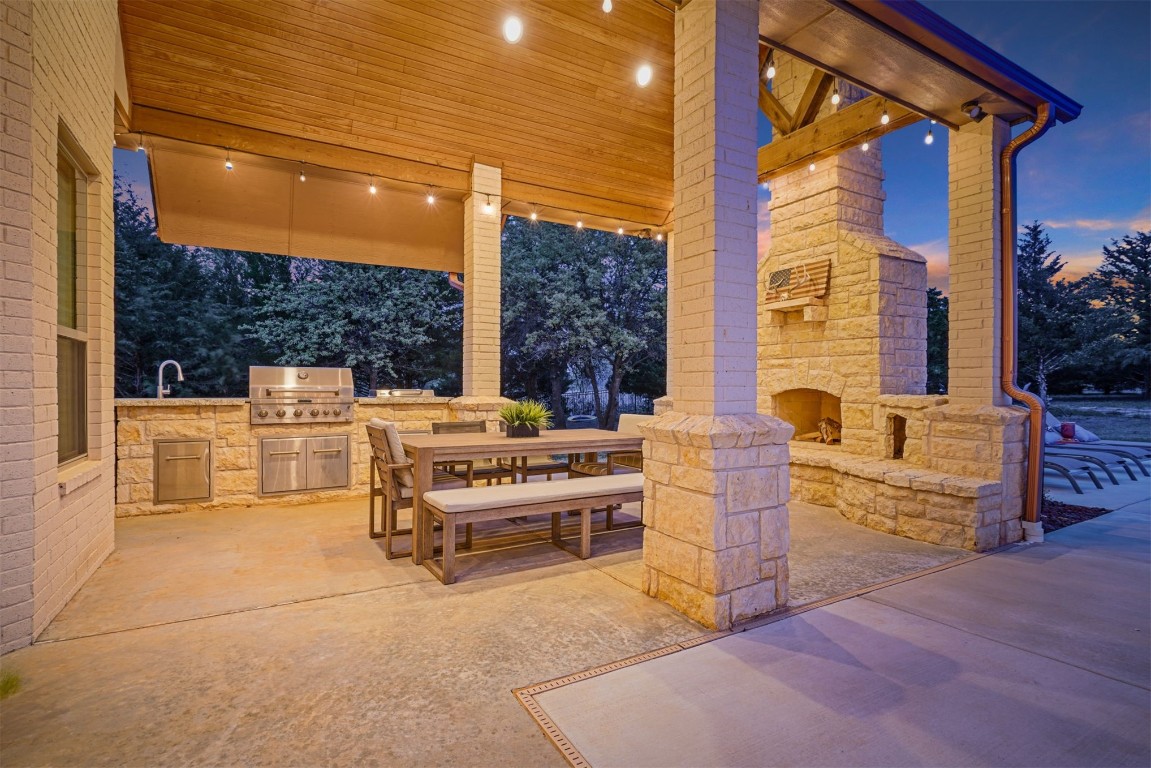 3600 Sea Ray Channel, Edmond, OK 73013 patio terrace at dusk featuring an outdoor stone fireplace, area for grilling, a grill, and sink