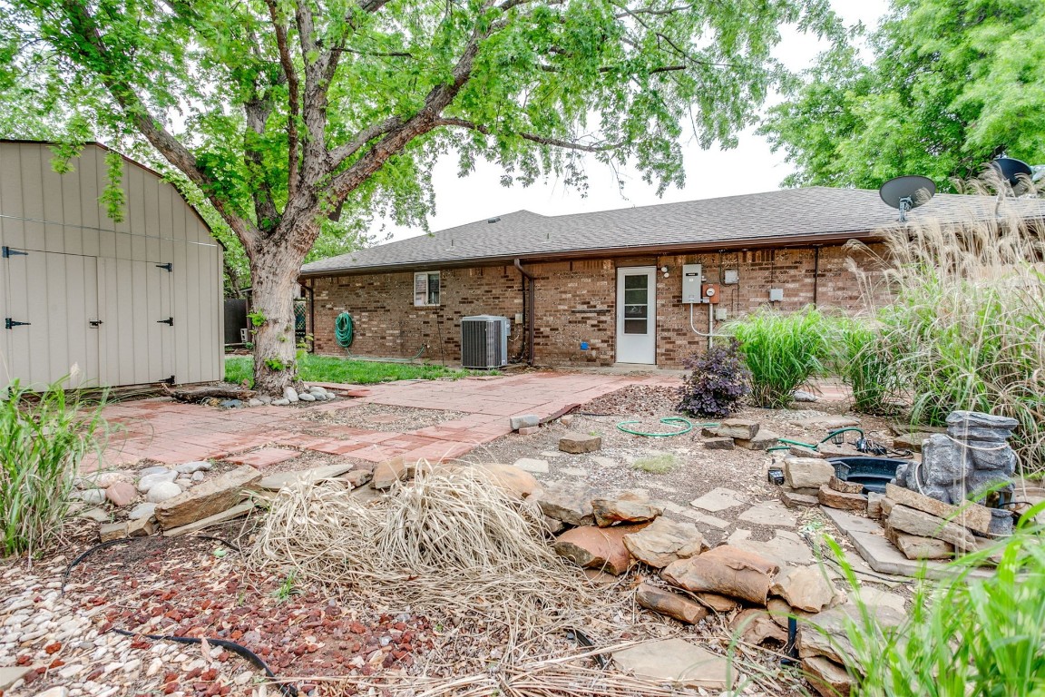 224 N Westminster Way, Mustang, OK 73064 back of house with central AC unit, a storage unit, and a patio