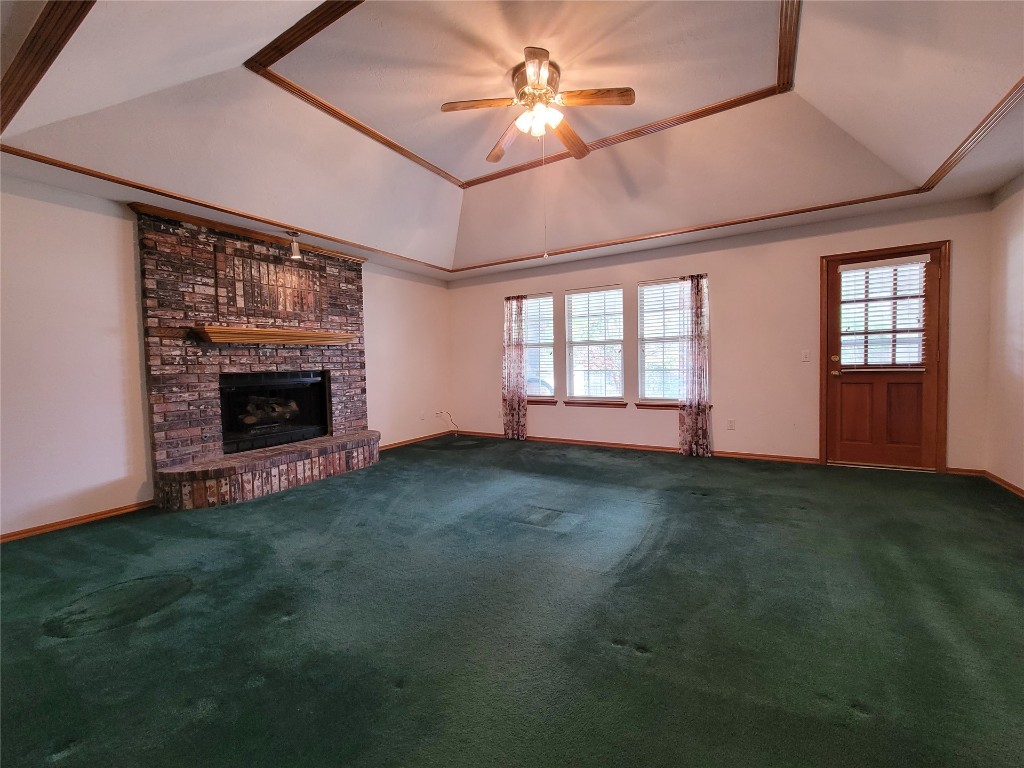 13125 Buckeye Court, Oklahoma City, OK 73170 unfurnished living room with brick wall, carpet floors, a fireplace, and a tray ceiling