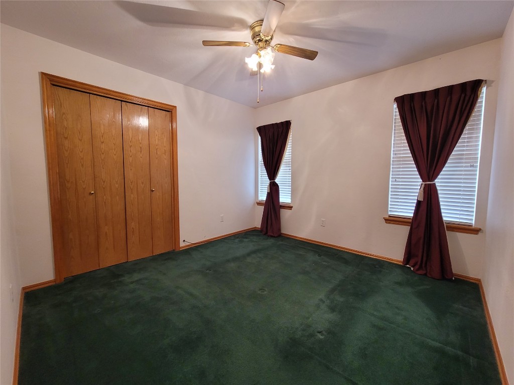 13125 Buckeye Court, Oklahoma City, OK 73170 unfurnished bedroom with a closet, ceiling fan, and dark colored carpet