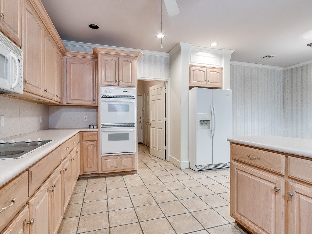 6508 NW 109th Place, Oklahoma City, OK 73162 kitchen featuring ornamental molding, white appliances, backsplash, and light tile floors