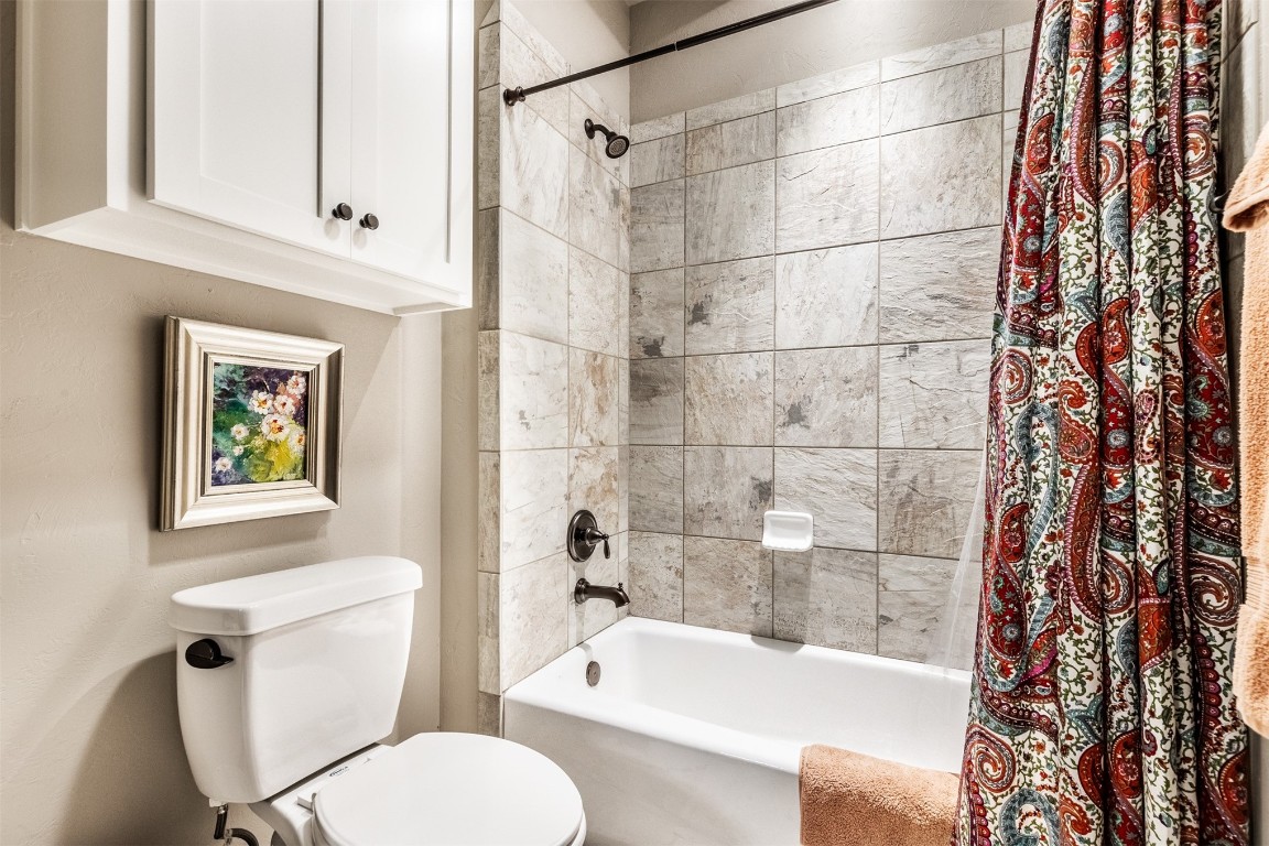 2709 Mesquite Lane, Edmond, OK 73034 bathroom featuring toilet and shower / bath combo with shower curtain