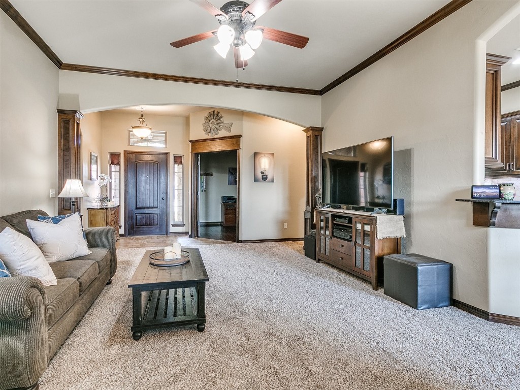 1900 Alexander Way, Yukon, OK 73099 carpeted living room featuring decorative columns, ceiling fan, and crown molding