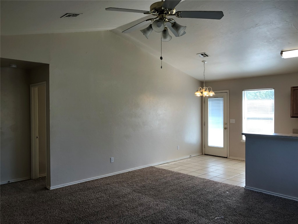Address Hidden empty room with ceiling fan with notable chandelier, vaulted ceiling, and light carpet