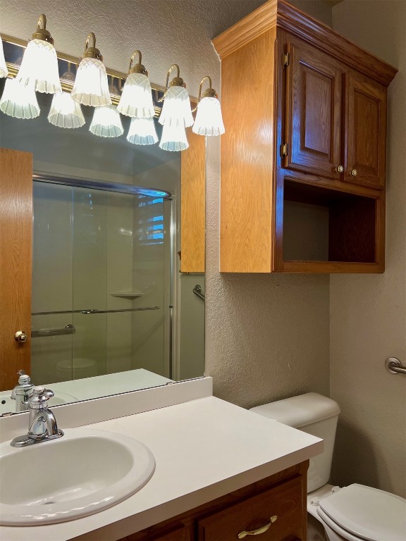 180 N Lakeside Terrace, Mustang, OK 73064 bathroom featuring walk in shower, vanity, and toilet