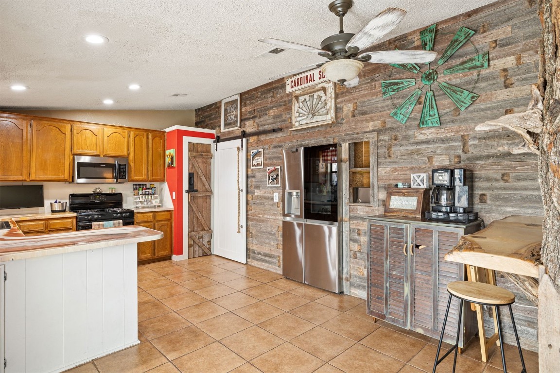 1816 SE 13th Street, Moore, OK 73160 kitchen with a barn door, wood walls, light tile floors, and stainless steel appliances