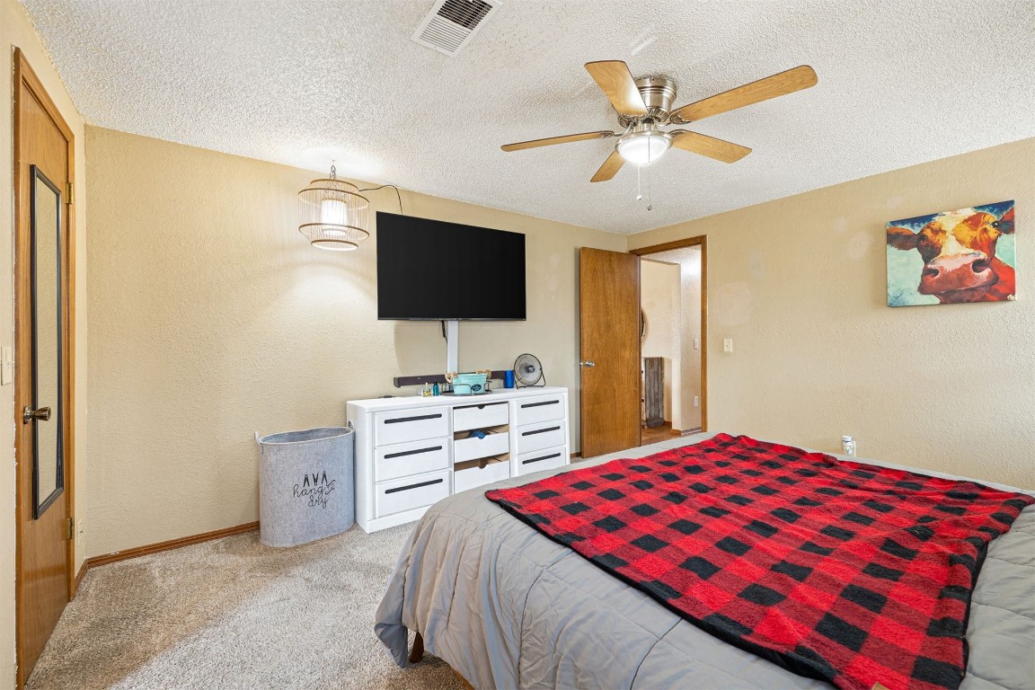 1816 SE 13th Street, Moore, OK 73160 carpeted bedroom featuring a textured ceiling and ceiling fan
