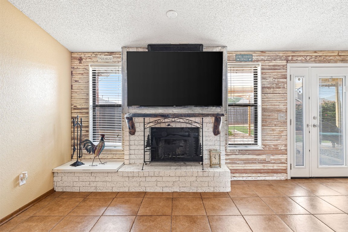 1816 SE 13th Street, Moore, OK 73160 unfurnished living room featuring a textured ceiling, tile floors, and wooden walls