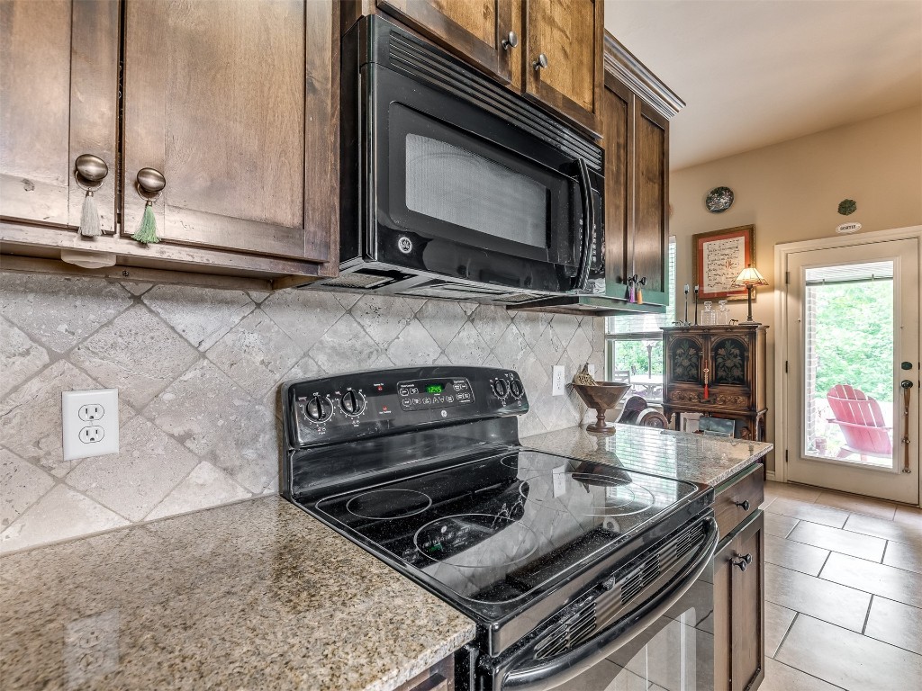 2924 Woodcrest Creek Drive, Norman, OK 73071 kitchen with backsplash, stone countertops, black appliances, and light tile floors