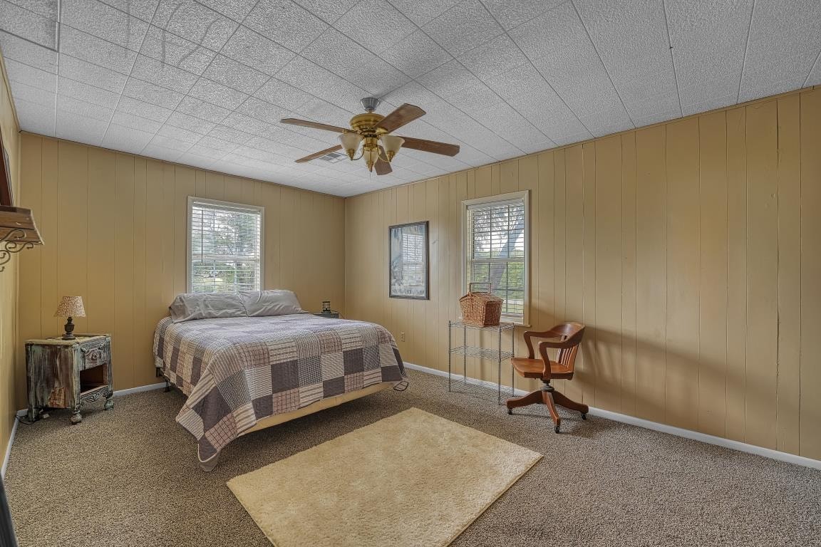 15448 S County Road 205 Road, Blair, OK 73526 carpeted bedroom with ceiling fan and wooden walls