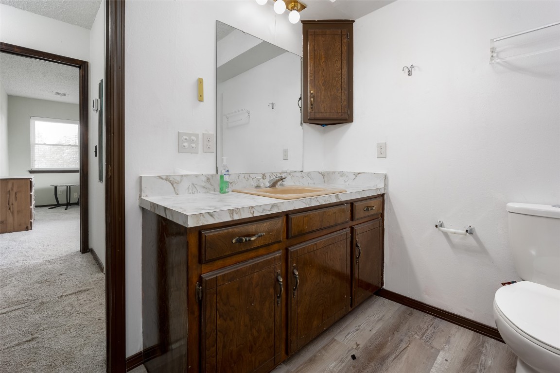 13494 290th Street, Blanchard, OK 73010 bathroom featuring a textured ceiling, toilet, vanity, and hardwood / wood-style floors