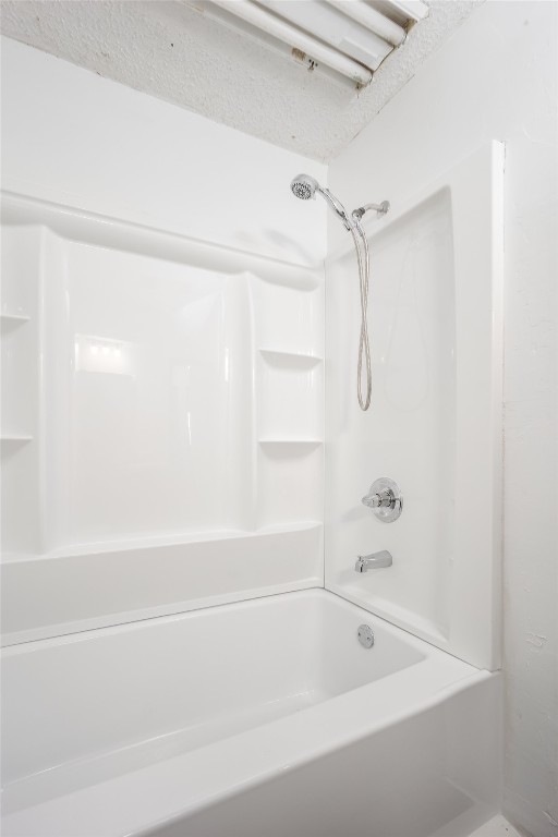 13494 290th Street, Blanchard, OK 73010 bathroom with bathtub / shower combination and a textured ceiling