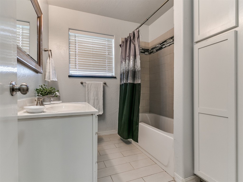 645 SW 3rd St, Moore, OK 73160 bathroom featuring vanity with extensive cabinet space, plenty of natural light, tile floors, and shower / tub combo with curtain