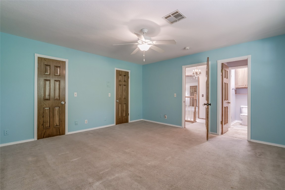 208 Crown Colony Court, Edmond, OK 73034 unfurnished bedroom with ceiling fan with notable chandelier, ensuite bath, carpet, and a closet