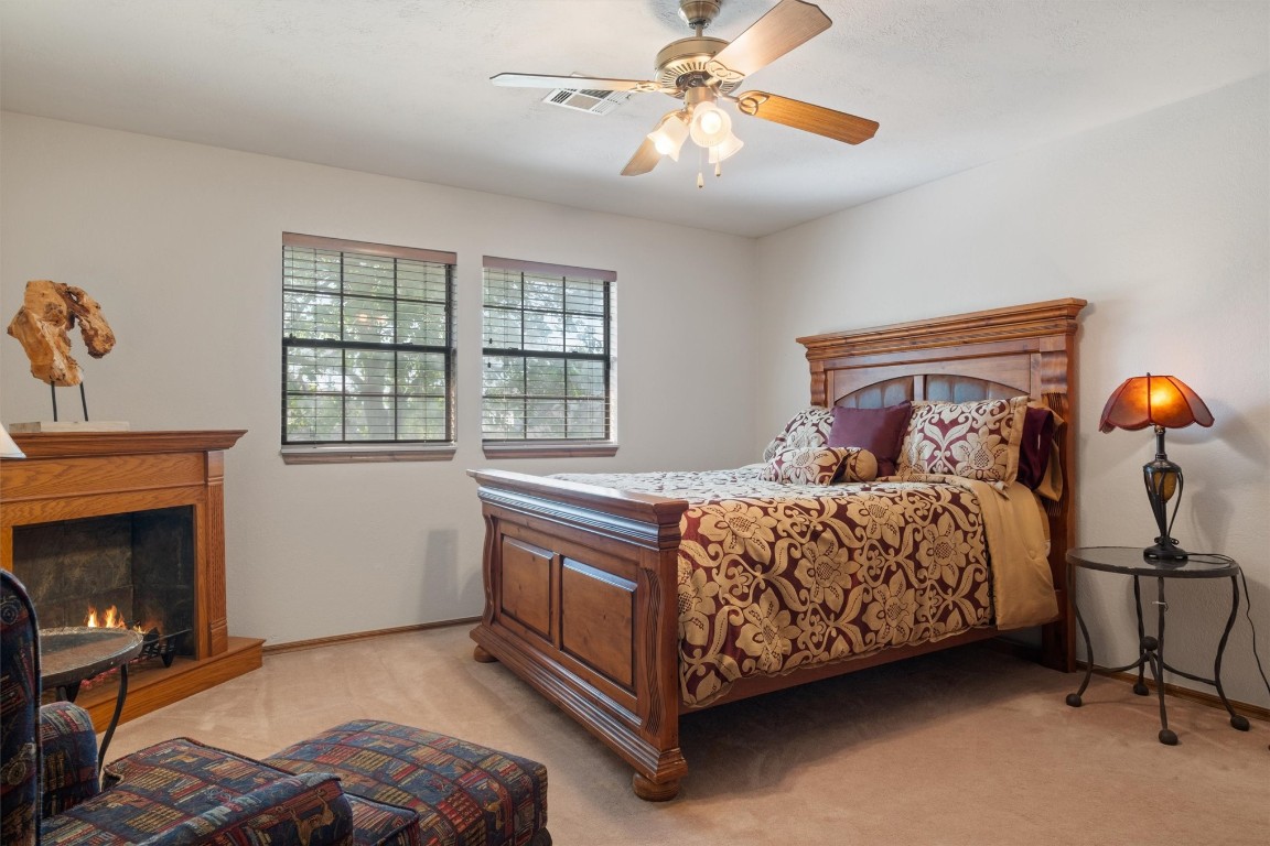 11517 Hackney Lane, Yukon, OK 73099 bedroom featuring light colored carpet, ceiling fan, and a fireplace