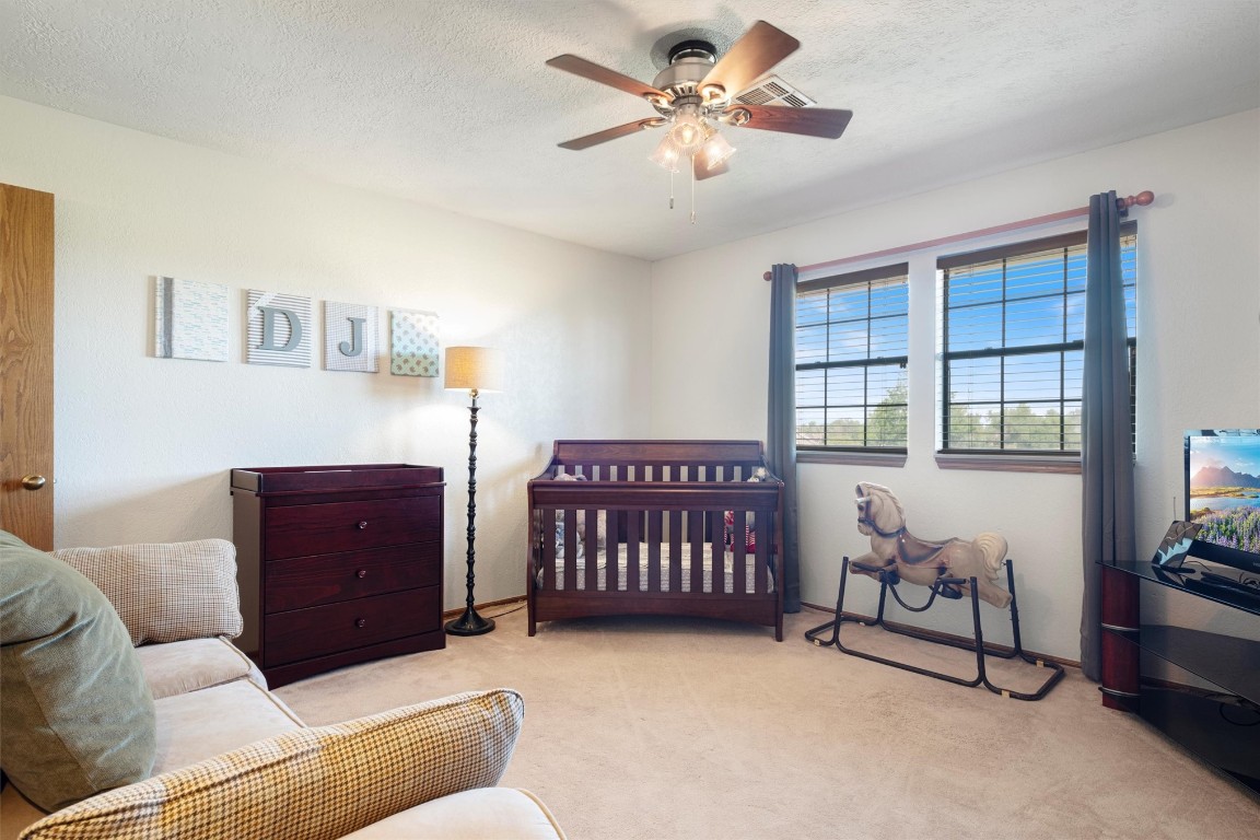 11517 Hackney Lane, Yukon, OK 73099 carpeted bedroom with ceiling fan, a crib, and a textured ceiling