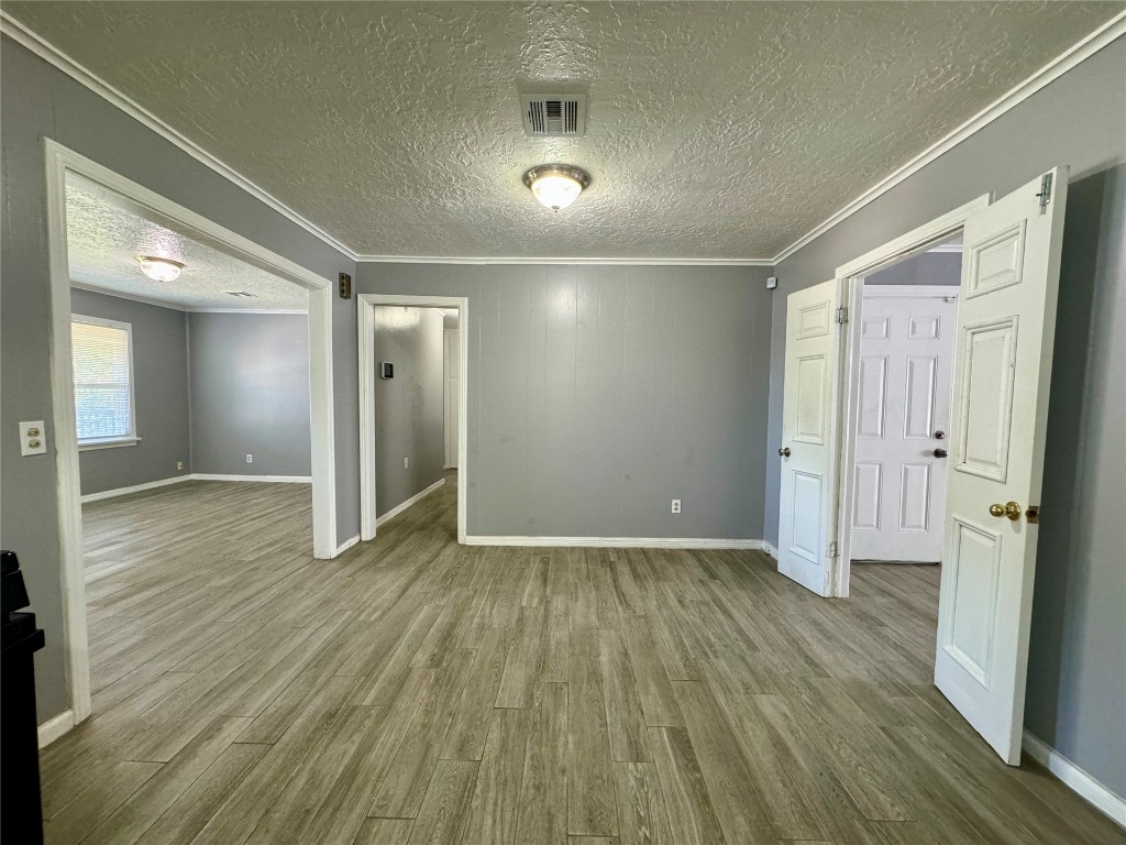 3328 NW 29th Street, Oklahoma City, OK 73107 empty room featuring hardwood / wood-style floors, ornamental molding, and a textured ceiling